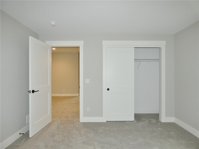 unfurnished bedroom with light colored carpet and a closet