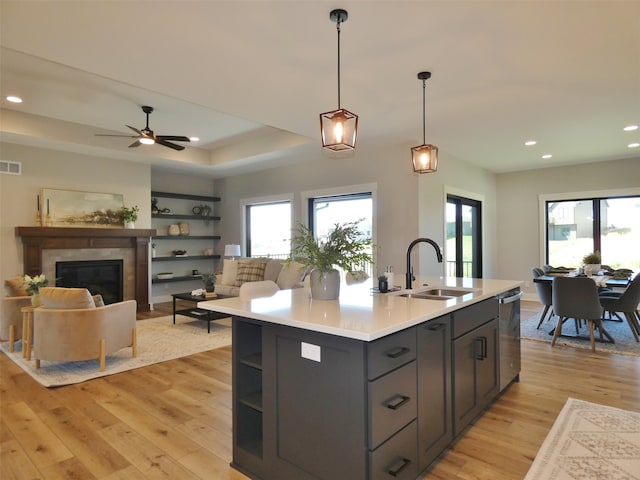 kitchen featuring a kitchen island with sink, light hardwood / wood-style flooring, sink, ceiling fan, and stainless steel dishwasher