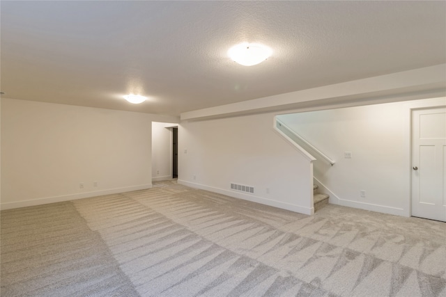 basement featuring light carpet and a textured ceiling