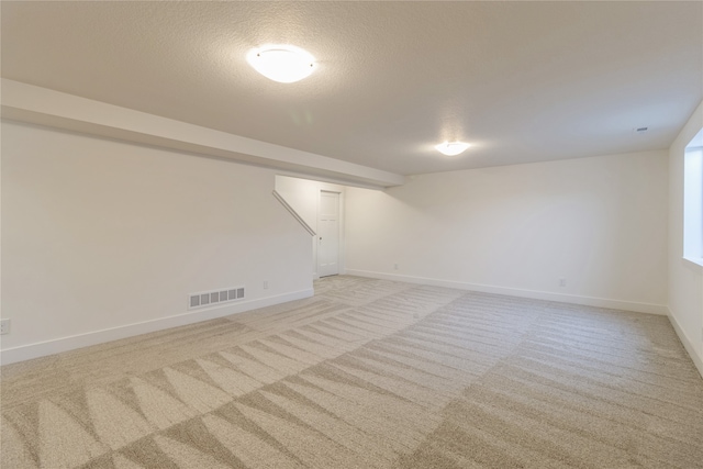 basement featuring light carpet and a textured ceiling