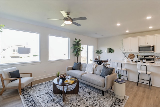 living room with light hardwood / wood-style flooring and ceiling fan