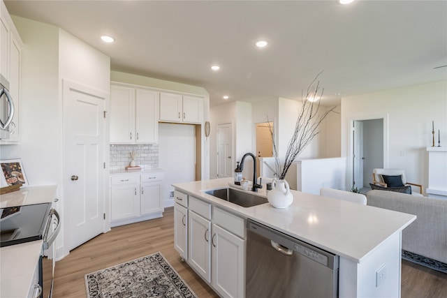 kitchen with white cabinetry, appliances with stainless steel finishes, sink, and an island with sink