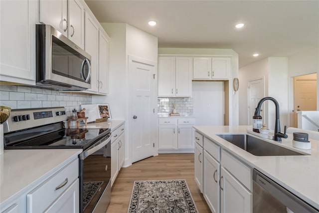 kitchen with white cabinets, stainless steel appliances, sink, and light wood-type flooring