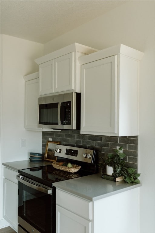 kitchen featuring white cabinets, tasteful backsplash, and appliances with stainless steel finishes