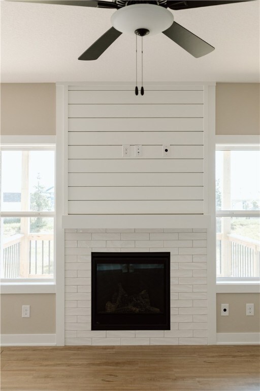 room details with light hardwood / wood-style floors, a brick fireplace, and ceiling fan