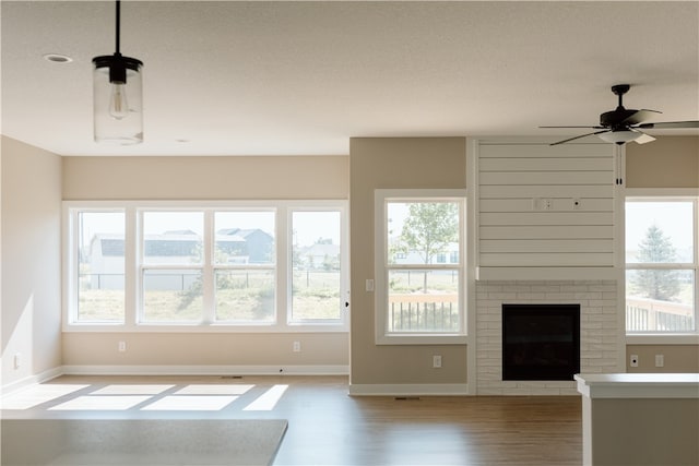 unfurnished living room featuring light hardwood / wood-style floors, ceiling fan, and a fireplace