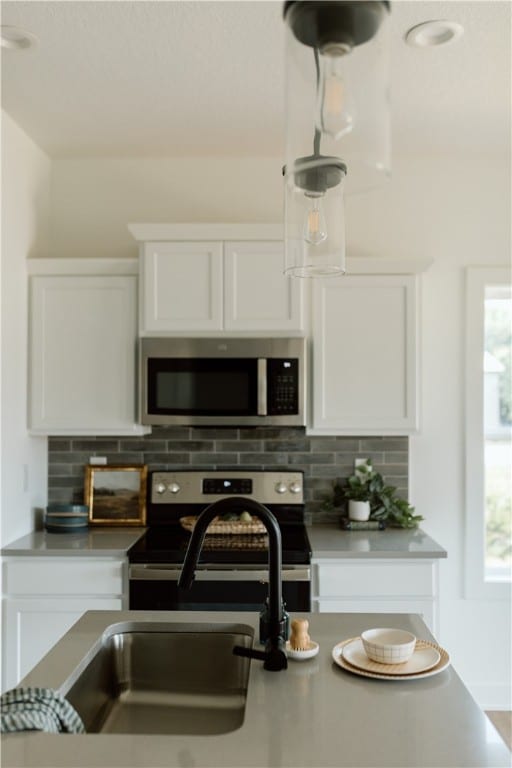 kitchen featuring tasteful backsplash, white cabinetry, a healthy amount of sunlight, and appliances with stainless steel finishes