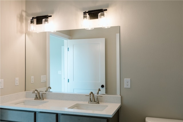 bathroom featuring oversized vanity, toilet, and dual sinks