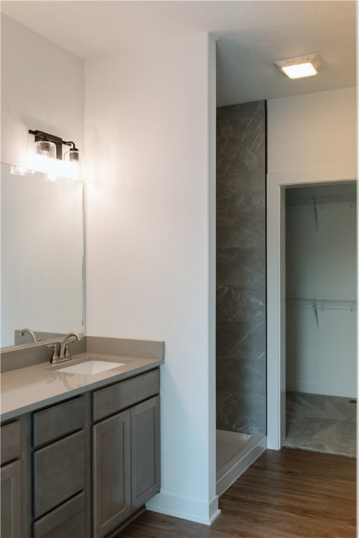 bathroom with vanity, a tile shower, and wood-type flooring