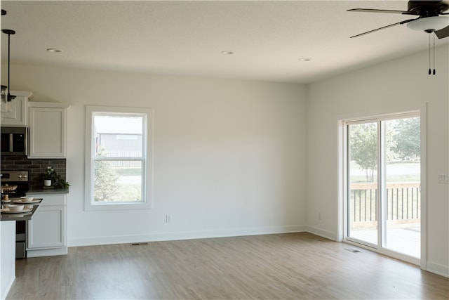 interior space with light hardwood / wood-style flooring, stainless steel appliances, white cabinets, and a wealth of natural light