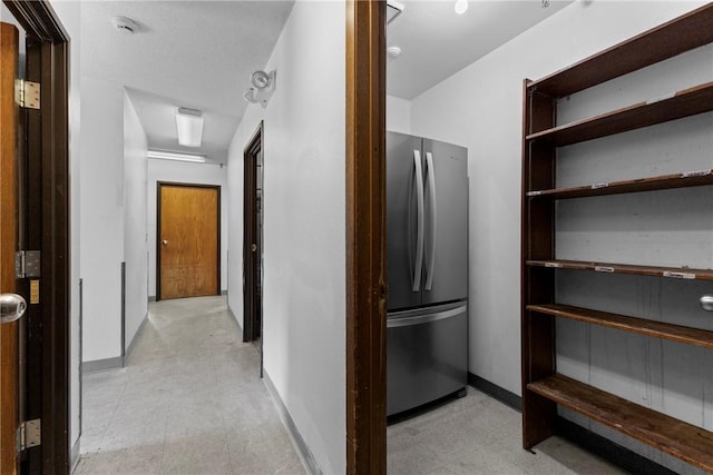 corridor featuring baseboards and light floors