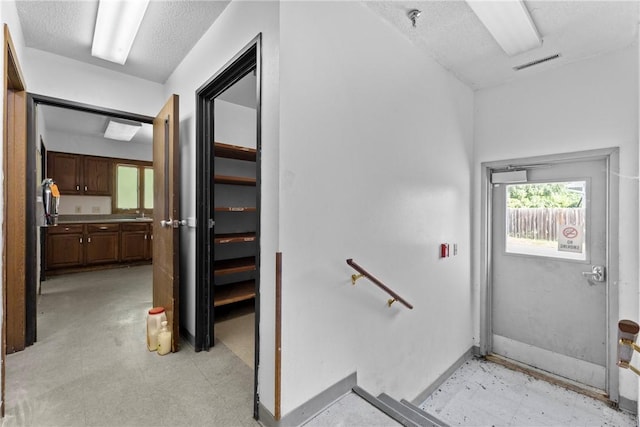 stairway featuring tile patterned floors, visible vents, baseboards, and a textured ceiling