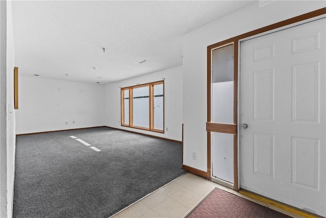 tiled empty room featuring carpet flooring and baseboards