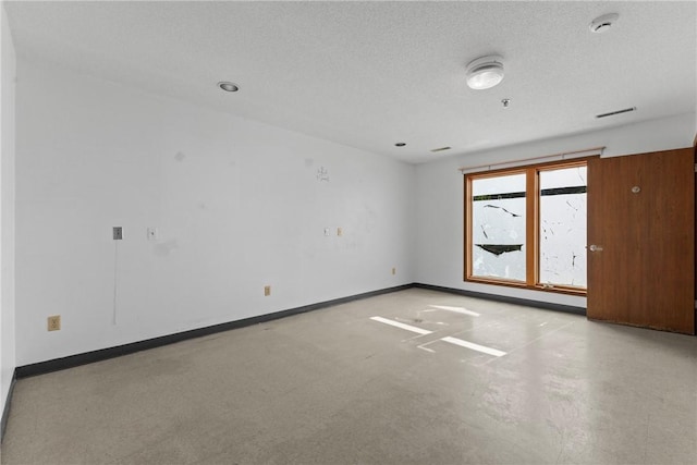 spare room featuring a textured ceiling and baseboards