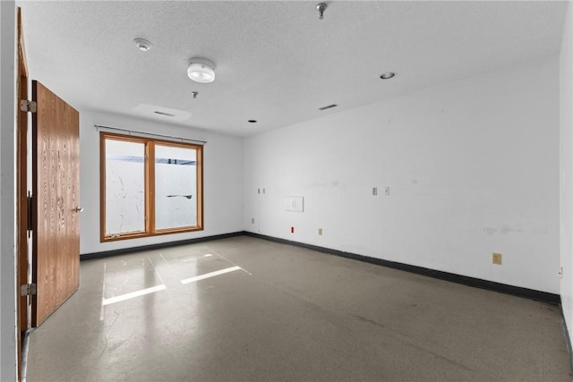 spare room featuring visible vents, baseboards, and a textured ceiling