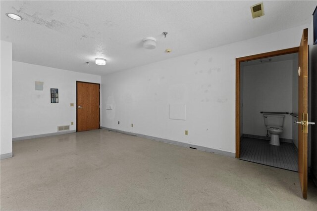 unfurnished room with visible vents, baseboards, and a textured ceiling