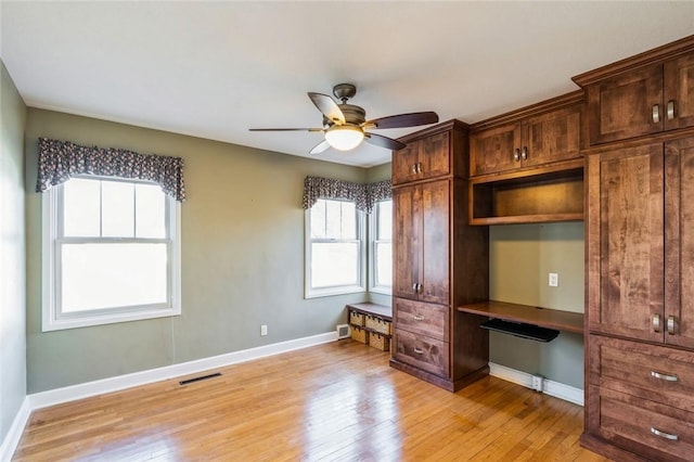 interior space with multiple windows, built in desk, and light wood-type flooring