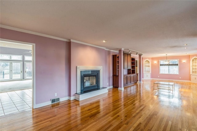 unfurnished living room with ceiling fan, ornamental molding, light hardwood / wood-style flooring, and a textured ceiling