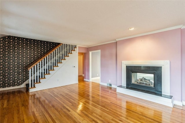 unfurnished living room with a tiled fireplace, hardwood / wood-style floors, and ornamental molding