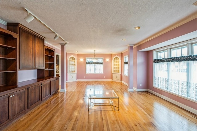 unfurnished living room featuring ornamental molding, rail lighting, a textured ceiling, and light wood-type flooring