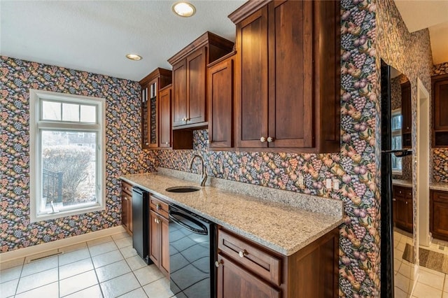 kitchen featuring light tile patterned floors, light stone countertops, sink, and black dishwasher