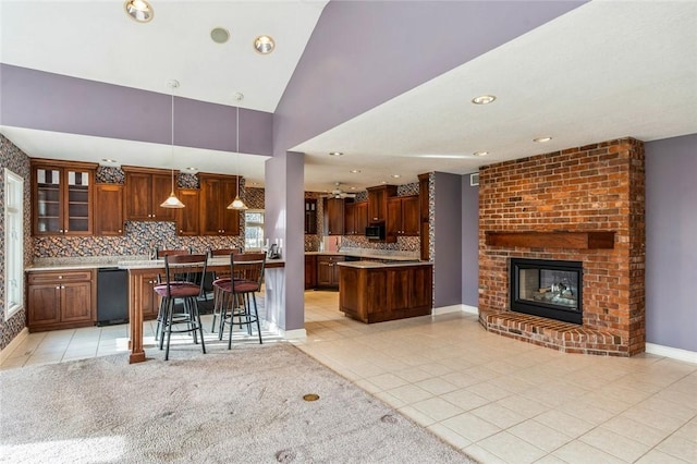 kitchen with light tile patterned flooring, decorative light fixtures, a brick fireplace, and a breakfast bar area