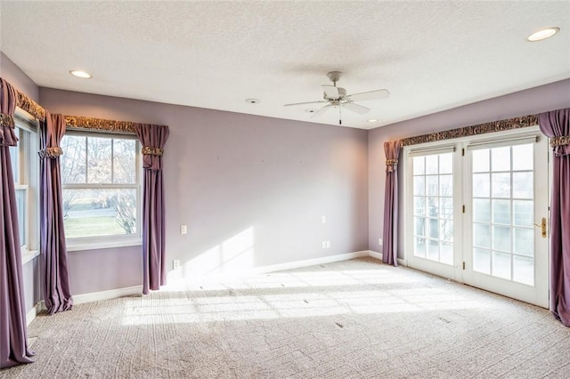 unfurnished room with ceiling fan, light colored carpet, and a textured ceiling