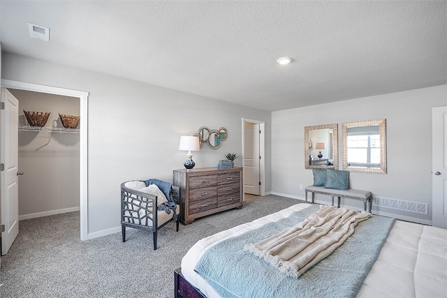 bedroom featuring a spacious closet, a closet, carpet floors, and a textured ceiling