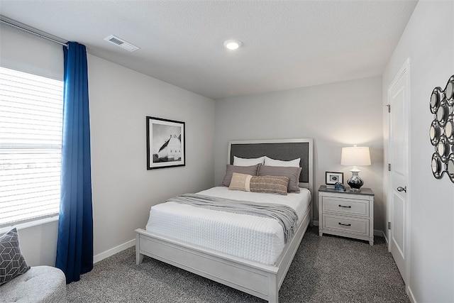 bedroom featuring a textured ceiling and dark carpet