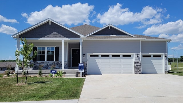 craftsman-style home with covered porch, a front yard, and a garage