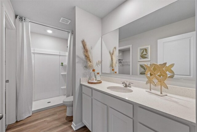 bathroom featuring wood-type flooring, vanity, toilet, and a shower with curtain