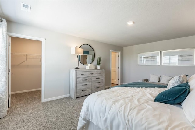 bedroom with light carpet, a walk in closet, and a closet