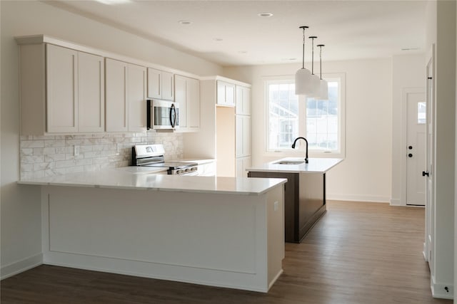 kitchen featuring sink, hanging light fixtures, dark hardwood / wood-style floors, appliances with stainless steel finishes, and kitchen peninsula