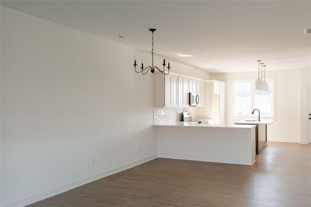 kitchen with kitchen peninsula, white electric range oven, hardwood / wood-style flooring, an inviting chandelier, and white cabinets