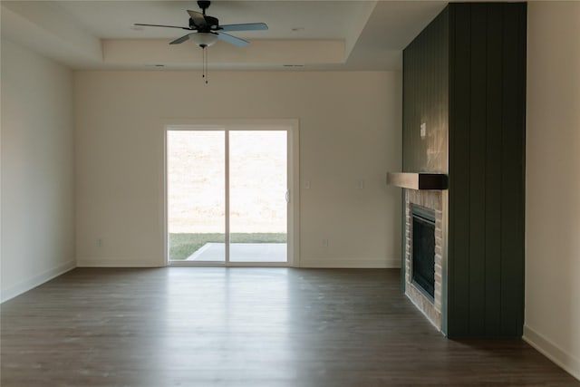 unfurnished living room with hardwood / wood-style floors, ceiling fan, and a tray ceiling