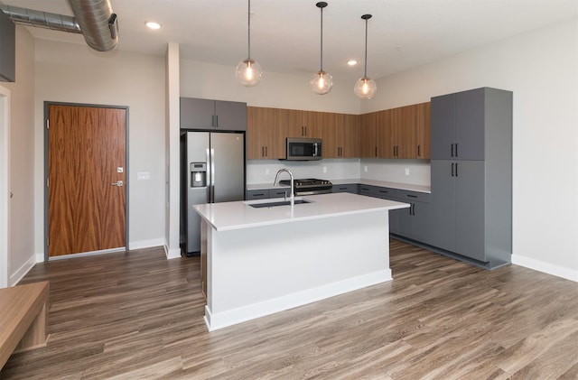 kitchen featuring a center island with sink, sink, appliances with stainless steel finishes, and a high ceiling