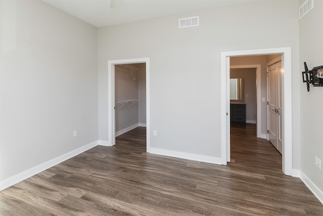 unfurnished bedroom featuring dark hardwood / wood-style floors, a spacious closet, and a closet