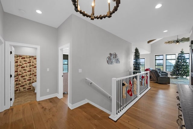 hallway with a chandelier, wood-type flooring, and lofted ceiling