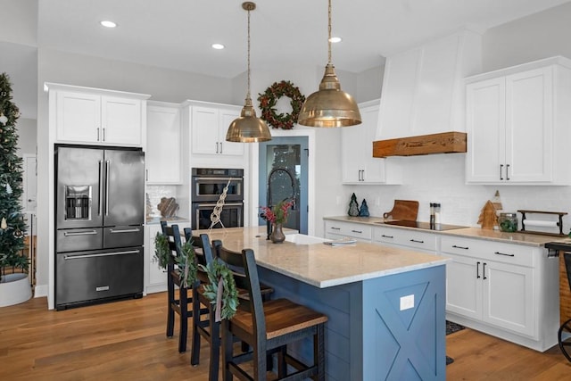 kitchen with a center island with sink, white cabinets, and stainless steel appliances