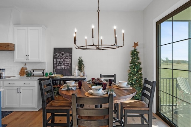 dining space with light hardwood / wood-style floors and a chandelier