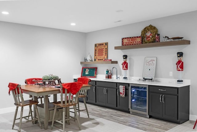 bar featuring sink, beverage cooler, and light hardwood / wood-style floors