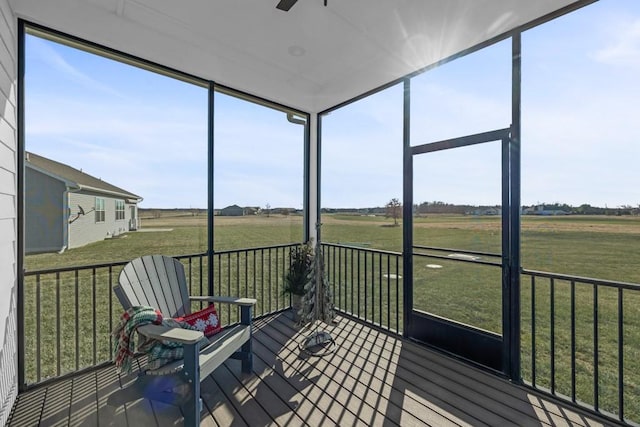 sunroom featuring ceiling fan and a rural view