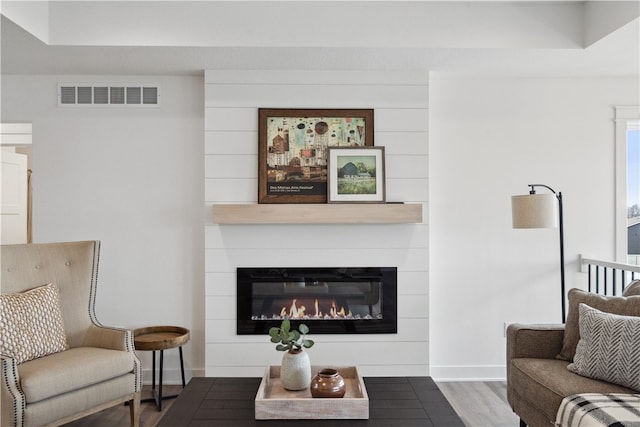 living room featuring dark hardwood / wood-style flooring and a large fireplace