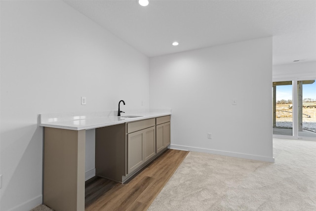 bar featuring gray cabinets, sink, and light hardwood / wood-style flooring