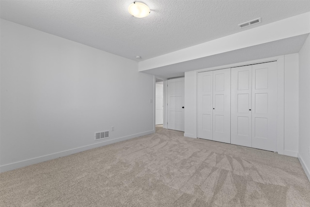 unfurnished bedroom with a textured ceiling, light colored carpet, and a closet