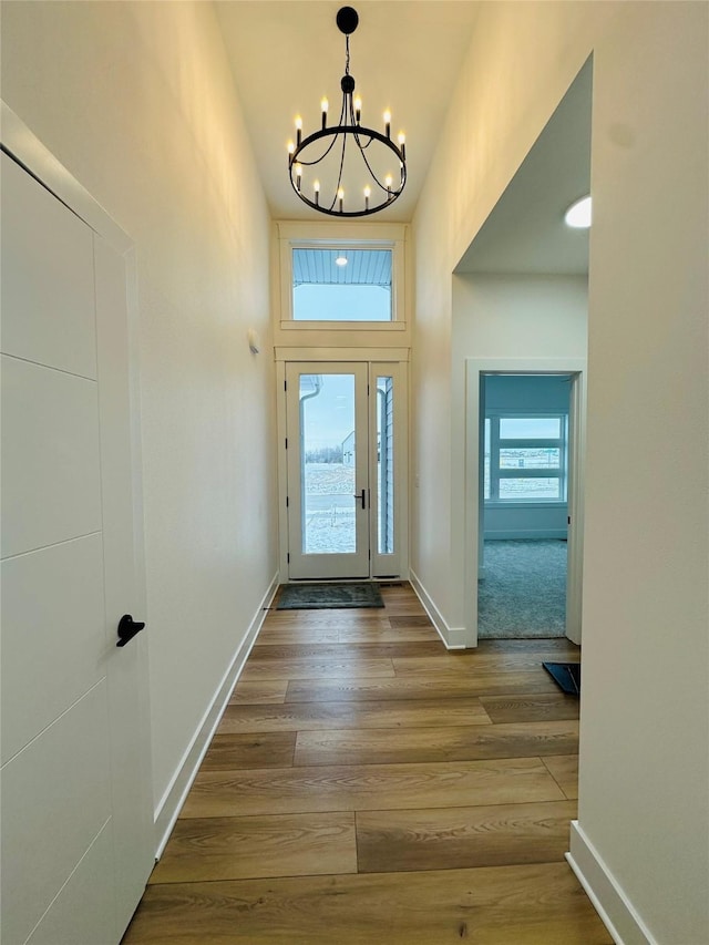 entryway featuring an inviting chandelier, plenty of natural light, and wood-type flooring