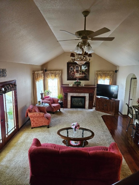 living room with lofted ceiling, dark colored carpet, ceiling fan, and a fireplace