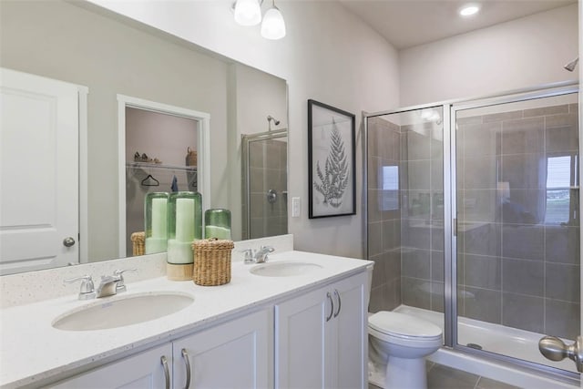 bathroom with a shower with shower door, toilet, double vanity, and tile flooring