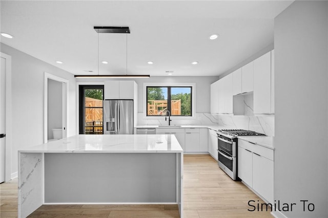 kitchen featuring a kitchen island, appliances with stainless steel finishes, pendant lighting, sink, and white cabinets