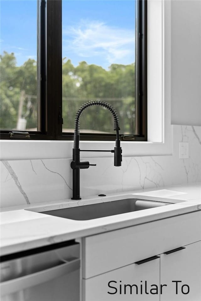 room details featuring sink, stainless steel dishwasher, and white cabinets